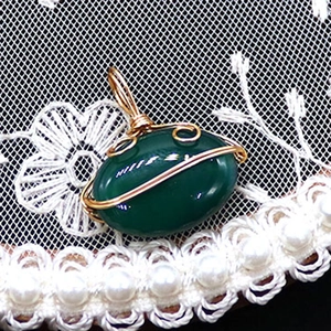 Macro detail of oval green striped agate pendant with golden hand-wrapped wire craftsmanship
