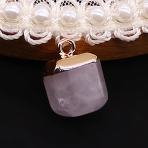 Detail shot of a purple translucent stone pendant with a gold clasp on a white lace choker
