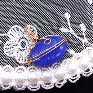 Macro view of blue agate stone pendant with intricate gold wire wrapping details