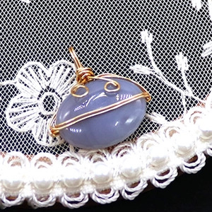 Macro shot of oval striped agate pendant with golden wire wrap and pearl accents