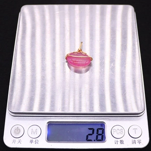 Macro shot of 2.8g pink natural stone pendant with gold wire wrap on digital scale