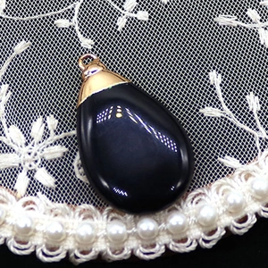Detailed view of teardrop black stone pendant with golden clasp on lace texture