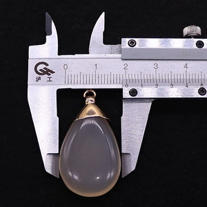 Macro shot of grey agate teardrop pendant measured with a caliper on black velvet