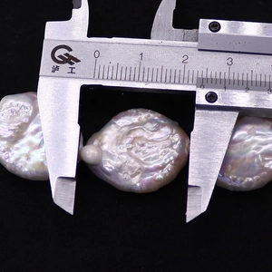 Macro shot measuring a 26mm irregular baroque pearl with a digital caliper tool