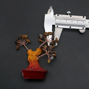 Detail view of a golden money tree figurine measured with a caliper showing 5.5cm width