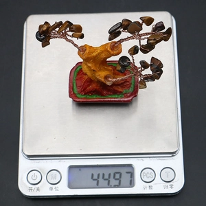 Tiger eye crystal tree weight display on scale featuring copper wire branches