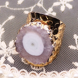 Détail d'une grande pierre de géode d'améthyste ronde sur une bague martelée dorée