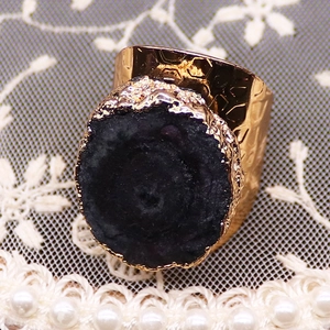 Détail macro d'une bague martelée dorée avec géode d'agate naturelle et feuilles d'or