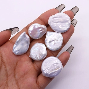 Hand holding six 20mm baroque freshwater pearls with iridescent purple luster for jewelry