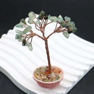 Gros plan d'un arbre en fil de cuivre avec feuilles de pierres vertes sur support blanc