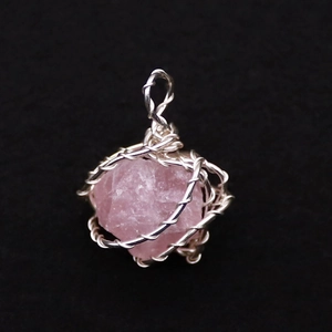 Makro-Detail des handgefertigten silbernen Drahtwickel-Anhängers mit rosa Rohkristall