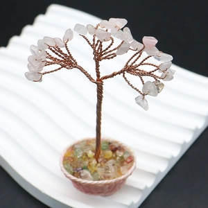 Gros plan d'un arbre de vie en quartz rose avec fils de cuivre sur panier tressé