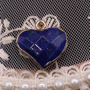 Macro-opname van hartvormige hanger met blauwe edelsteen en vergulde metalen rand