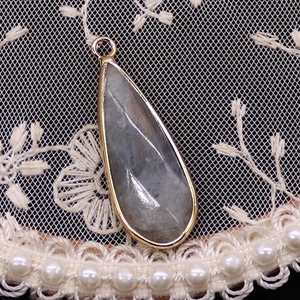 Vue détaillée du pendentif en pierre naturelle facettée et monture dorée sur dentelle