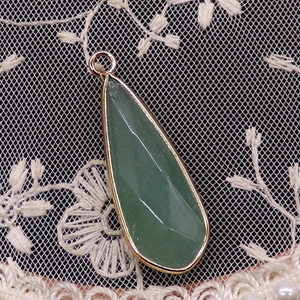 Détail macro du pendentif en pierre verte facettée avec une élégante bordure en métal doré