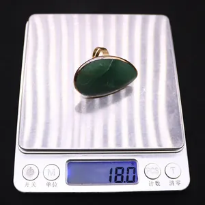 Detail showing an adjustable gold ring with a large oval green natural stone on a scale