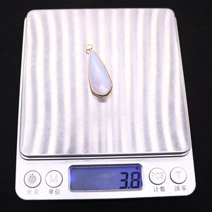 Vue détaillée d'un pendentif goutte en opale blanche pesant 3,8 g sur une balance de précision