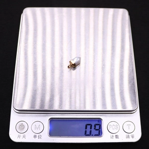 Macro-opname van een zeshoekige natuursteen hanger op een weegschaal van 0,9 gram