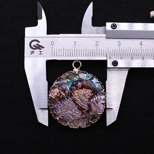 Detail eines 25mm runden Abalone Muschel Anhängers mit goldenem Zackenrand auf dem Messschieber