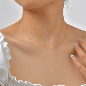 Primer plano de collar de cadena minimalista de acero inoxidable oro 18K usado por modelo