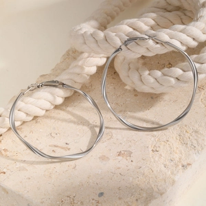 Close-up of silver stainless steel Mobius hoop earrings with twisted wave design on stone