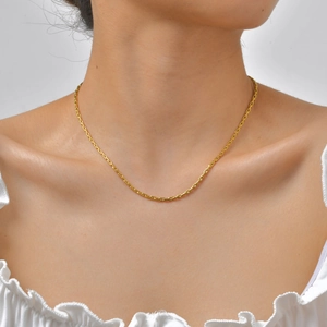 Primer plano de una delicada cadena de acero inoxidable bañada en oro de 18K en el cuello