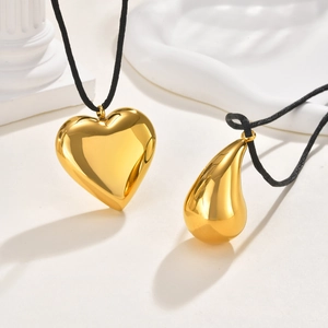 Minimalist 18K gold hollow heart and teardrop necklaces on architectural art props
