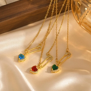 Détail macro de trois pendentifs cœur zircon épingle à nourrice sur chaînes dorées