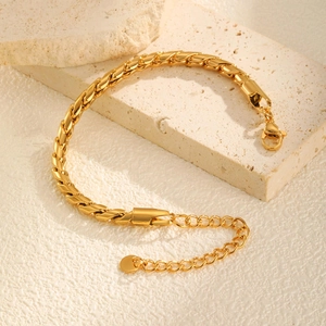 Dettaglio di un bracciale a catena intrecciata dorata con chiusura a moschettone su pietra