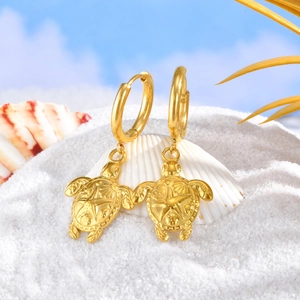 Boucles d'oreilles créoles tortue dorée avec relief d'étoile de mer sur sable blanc