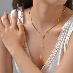 Close-up of a tricolor rosary necklace with oval medal and gold cross on a model