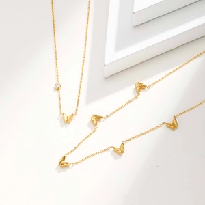 Detail von goldenen Schmetterlingsketten mit Zirkonia auf weißem minimalistischem Dekor