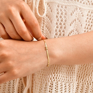 Bracelet chaîne fleur dorée élégant avec breloque nœud sur poignet femme