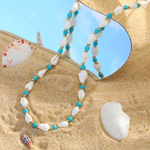 Böhmische goldene Edelstahlkette mit Meeresmuscheln und Türkisperlen auf dem Sand