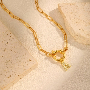 Macro view of 18K gold paperclip chain necklace with sparkling letter A pendant