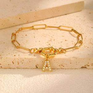 Detail van 18K vergulde armband met letter A hanger en witte zirkoon op paperclip ketting
