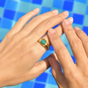 Vintage 18K gold stainless steel ring with oval turquoise on hand by a blue pool