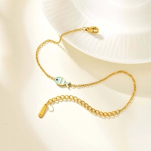 Detalle de una pulsera de acero bañada en oro 18K con un colgante de pez a rayas azules