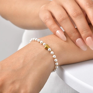 Détail d'un élégant bracelet de perles avec pendentif cœur doré sur un poignet