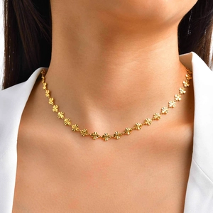Elegante collana a quadrifoglio in oro con petali testurizzati indossata da una modella