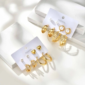 Elegantes Set aus goldfarbenen Herz-Zirkonia-Ohrringen mit Creolen auf Marmorhintergrund
