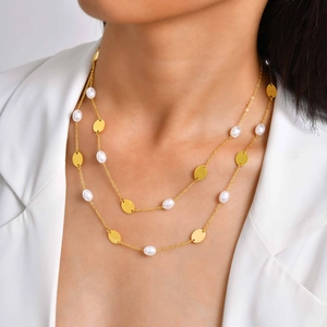 Détail d'un collier doré multicouche avec pendentifs ovales et perles sur mannequin
