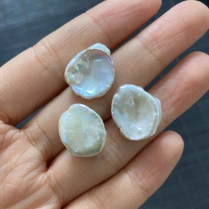 Three natural white baroque freshwater pearls with iridescent luster held in palm