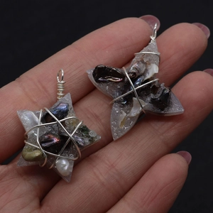 Detail of star-shaped handmade pendants with wire wrapping and dark pearl inlays
