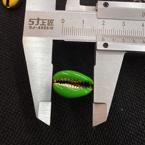 Measuring green conch shell bead with calipers showing the 18mm width detail
