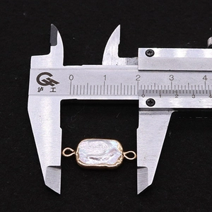 Macro detail of rectangular baroque pearl connector showing 21mm size on a caliper