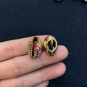 Détail de pendentifs coquillage dorés avec motif œil grec pour création de bijoux DIY