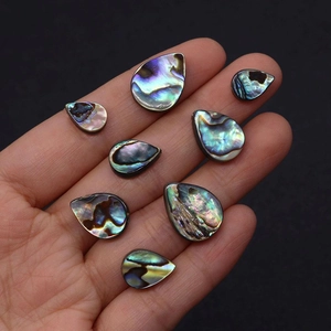 Détail macro de perles en nacre d'abalone en forme de goutte sur une paume