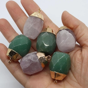Faceted rose quartz and aventurine stone pendants with gold-plated caps on palm
