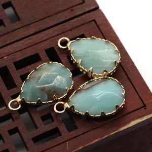 Trois pendentifs Amazonite en forme de goutte avec bordure dorée sur plateau en bois